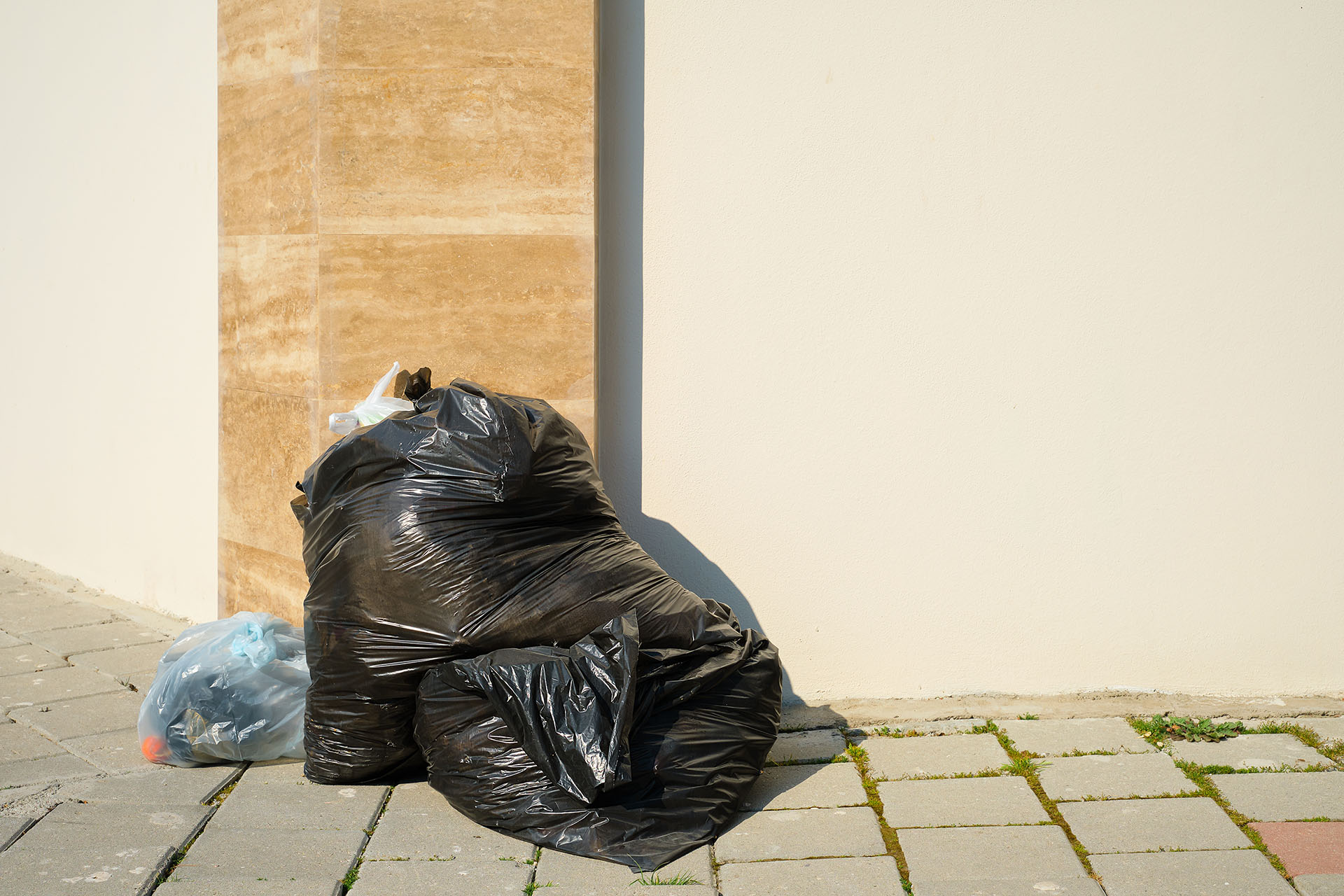 pile of garbage in black plastic garbage bags on the sidewalk by the road in a big city, space for text, garbage from pollution. Waste recycling, recycling and city ecology
